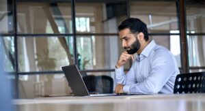 Man looking at a laptop and wondering when to hire an employment lawyer in Connecticut.