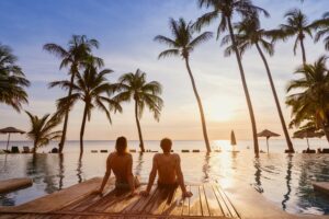 A couple watches a sunset near the pool at a resort as they wonder about the vacation pay laws in Connecticut.
