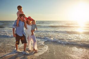 A young family with two kids is walking on the beach, enjoying their holiday. Understanding vacation pay laws in Massachusetts is essential for protecting your rights as an employee.