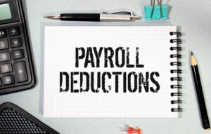 The words "payroll deductions" written on a spiral notepad to symbolize the question of what wage deductions are illegal under the FLSA.